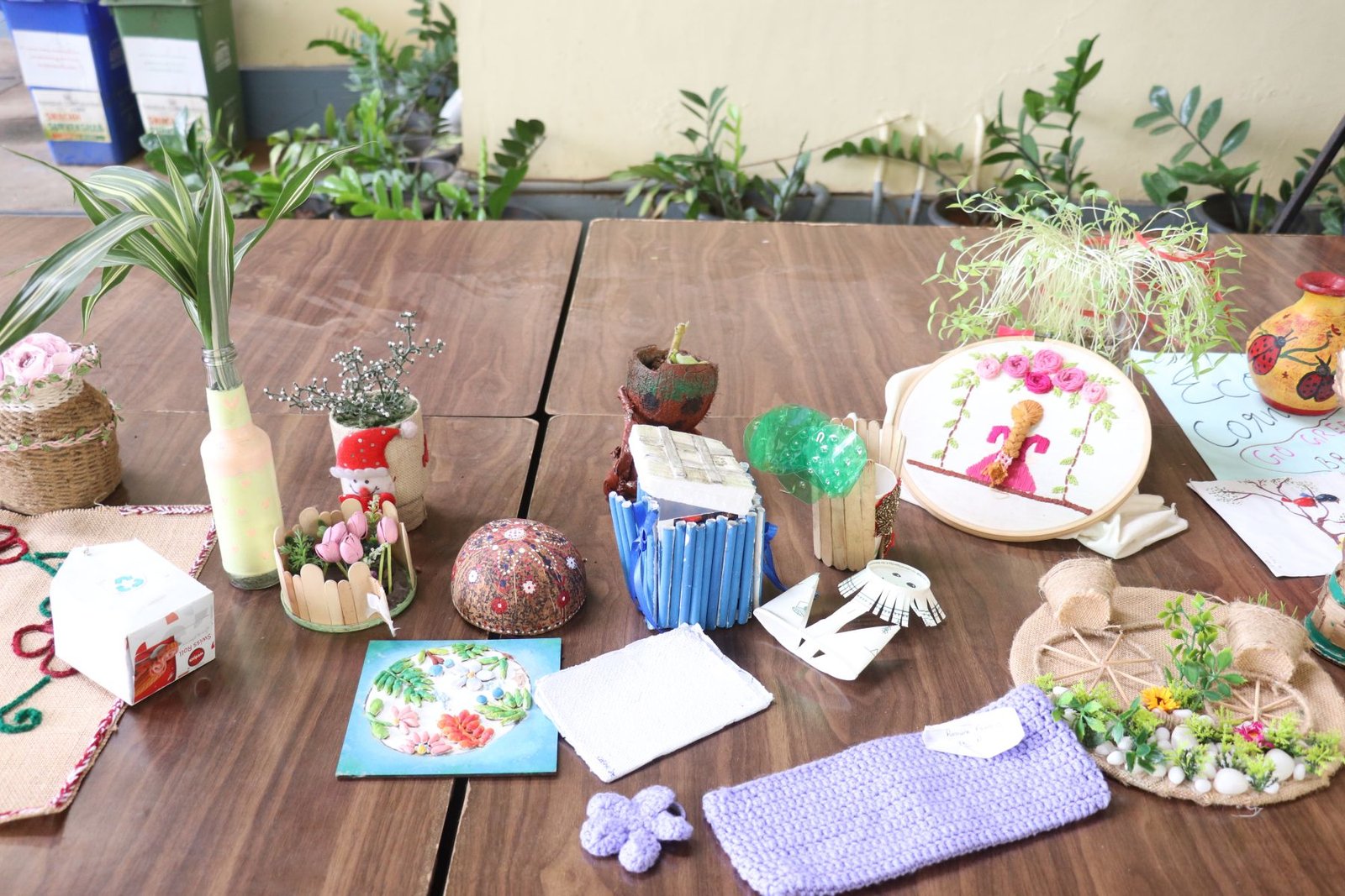 A table full of student-made crafts and small green displays